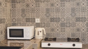 Une cuisine équipée d’un four à micro-ondes, d’une bouilloire et d’une cuisinière à gaz.