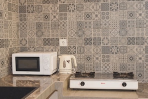 Una cocina equipada con microondas, hervidor y estufa a gas.