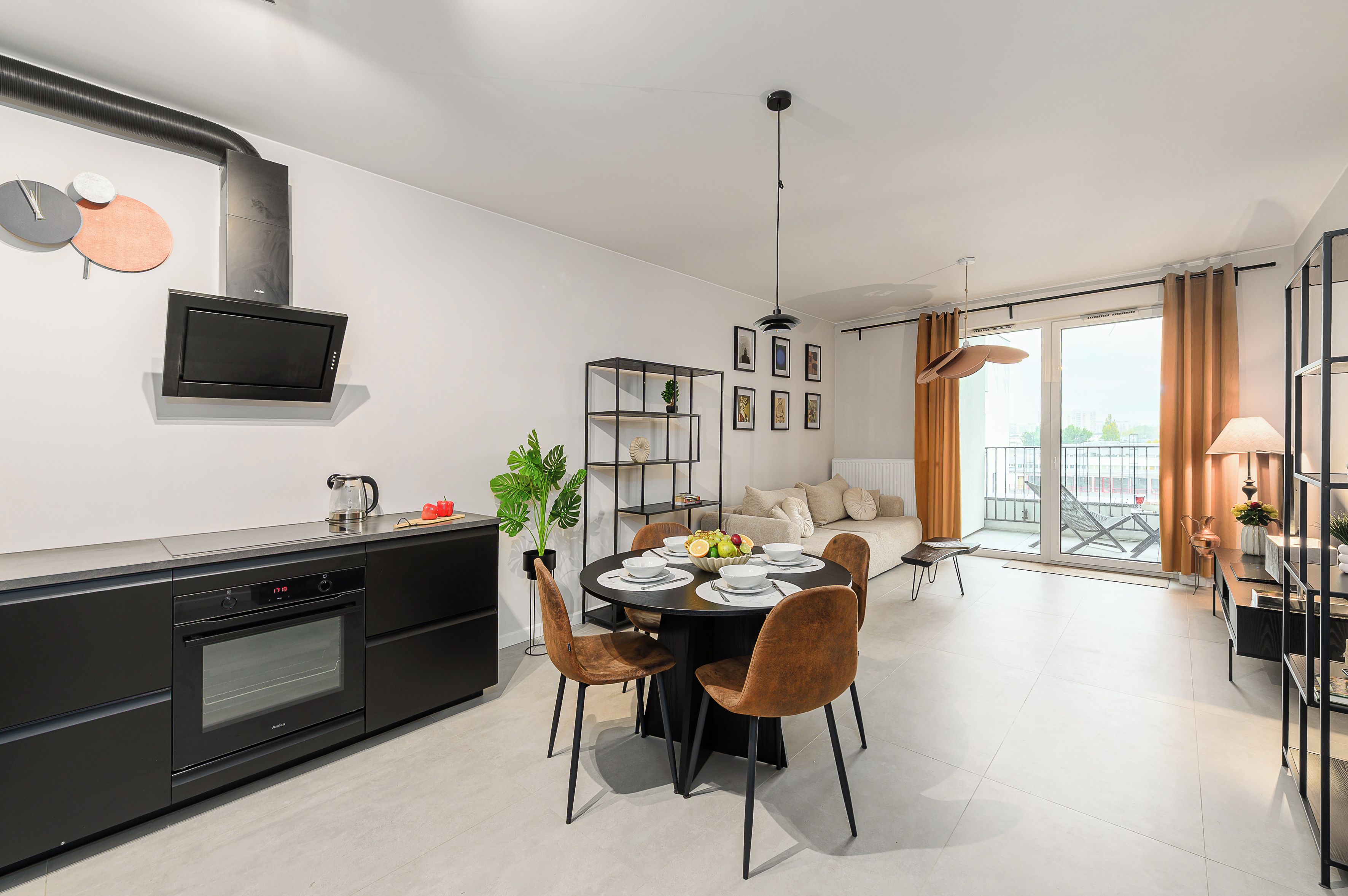 A modern kitchen with a built-in oven and a dining area with a round table and chairs.