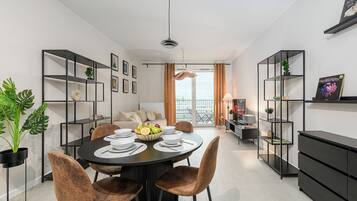 A modern living space with a dining area, black shelving units, and a view to the outside.