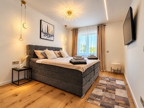 A modern bedroom with a large bed, a bedside table, a TV mounted on the wall, and a window with curtains. - Modern Villa Istria in Nedescina (Nedescina)