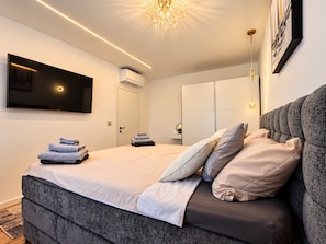 A modern bedroom with a large bed, a flat-screen TV mounted on the wall, and a ceiling light fixture. - Modern Villa Istria in Nedescina (Nedescina)