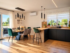 A modern kitchen with a central island, bar stools, and a dining area with chairs. - Modern Villa Istria in Nedescina (Nedescina)