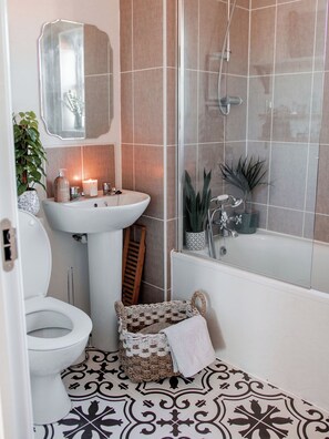 A bathroom with a white sink, a toilet, a shower, and a mirror. - Short term stay available in 1 bed flat (London)