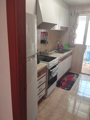 A compact kitchen with a stove, oven, sink, and cabinets. - The El Tiburon vacation rental is located 70 meters from the beach and the Maritim Passeig. (Grau i Platja)