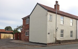 Ein zweistöckiges Haus mit einer Ziegel-Fassade und einem weißen Anbau.