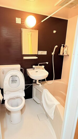 Une petite salle de bain comprenant des toilettes, un lavabo et une baignoire.