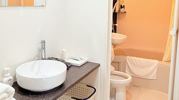 A modern bathroom with a white sink, a mirror, and a shower area visible through a glass door.