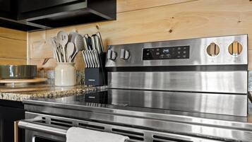 Una cocina de acero inoxidable con encimera de granito, un bloque de cuchillos Farberware y un horno de acero inoxidable.