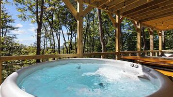 Un bain à remous situé sous une terrasse en bois, avec vue sur les arbres.