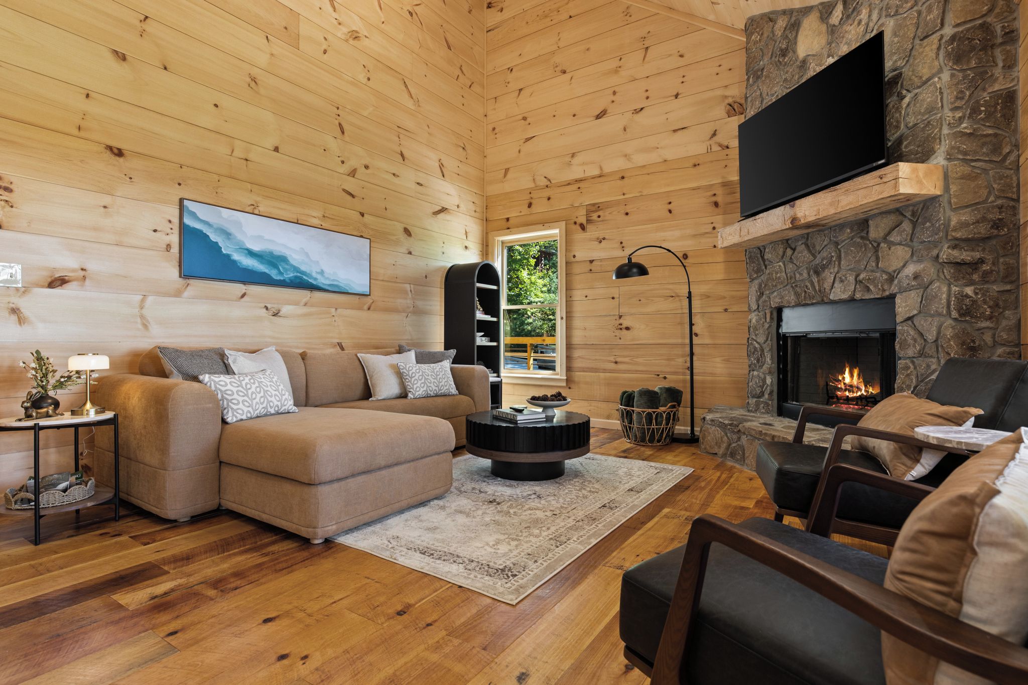 Un intérieur de chalet chaleureux avec une cheminée, des murs en bois, un canapé, une table basse et un téléviseur.