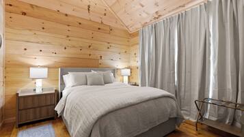 Un dormitorio con paneles de madera, una cama, mesitas de noche y un ventanal con cortinas.