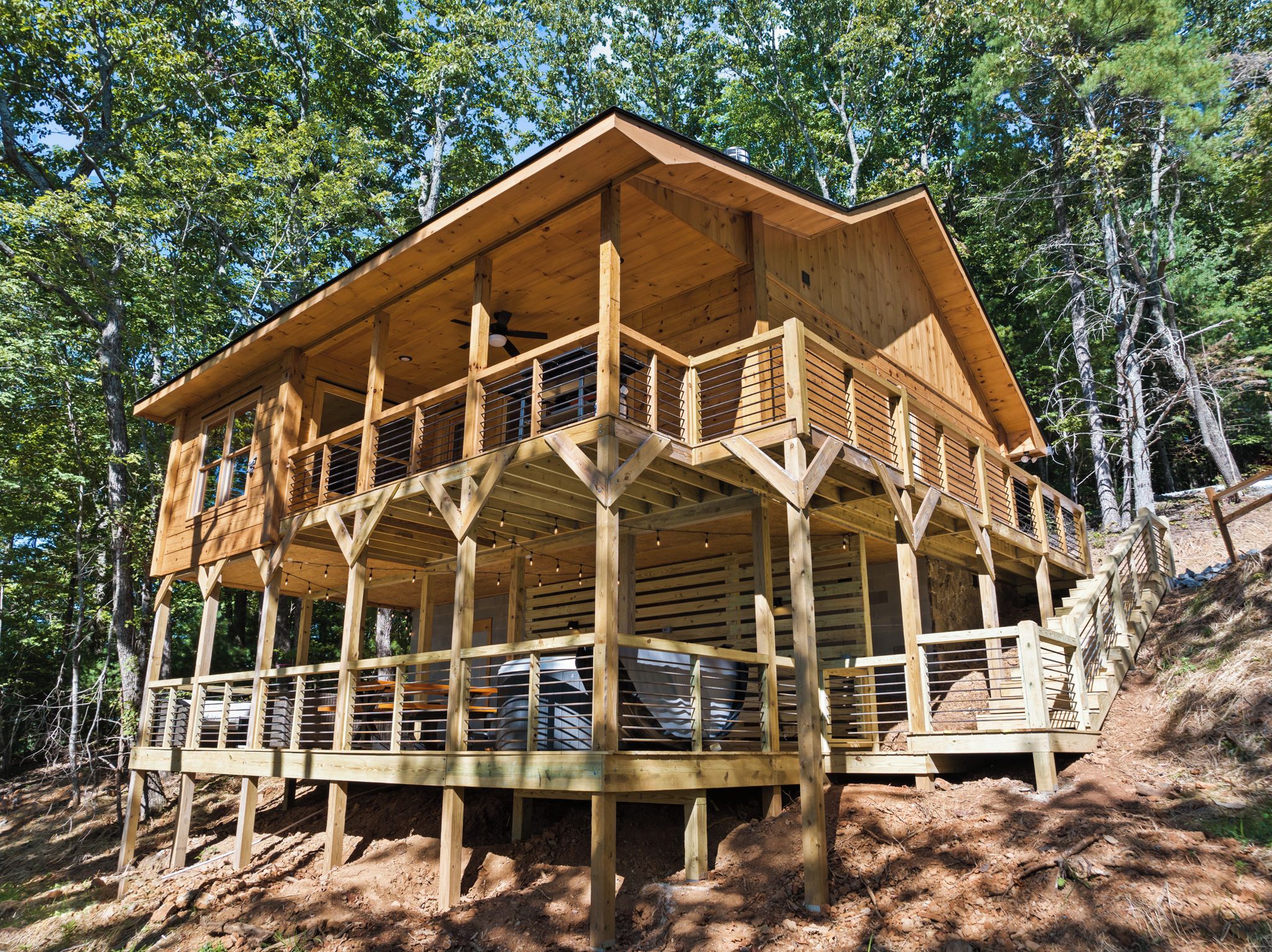 A wooden cabin with a balcony, surrounded by trees.