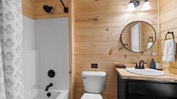 Une salle de bain équipée d’une baignoire, de toilettes, d’un lavabo et d’un miroir.