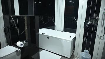 A modern bathroom with a toilet, bidet, and a bathtub.