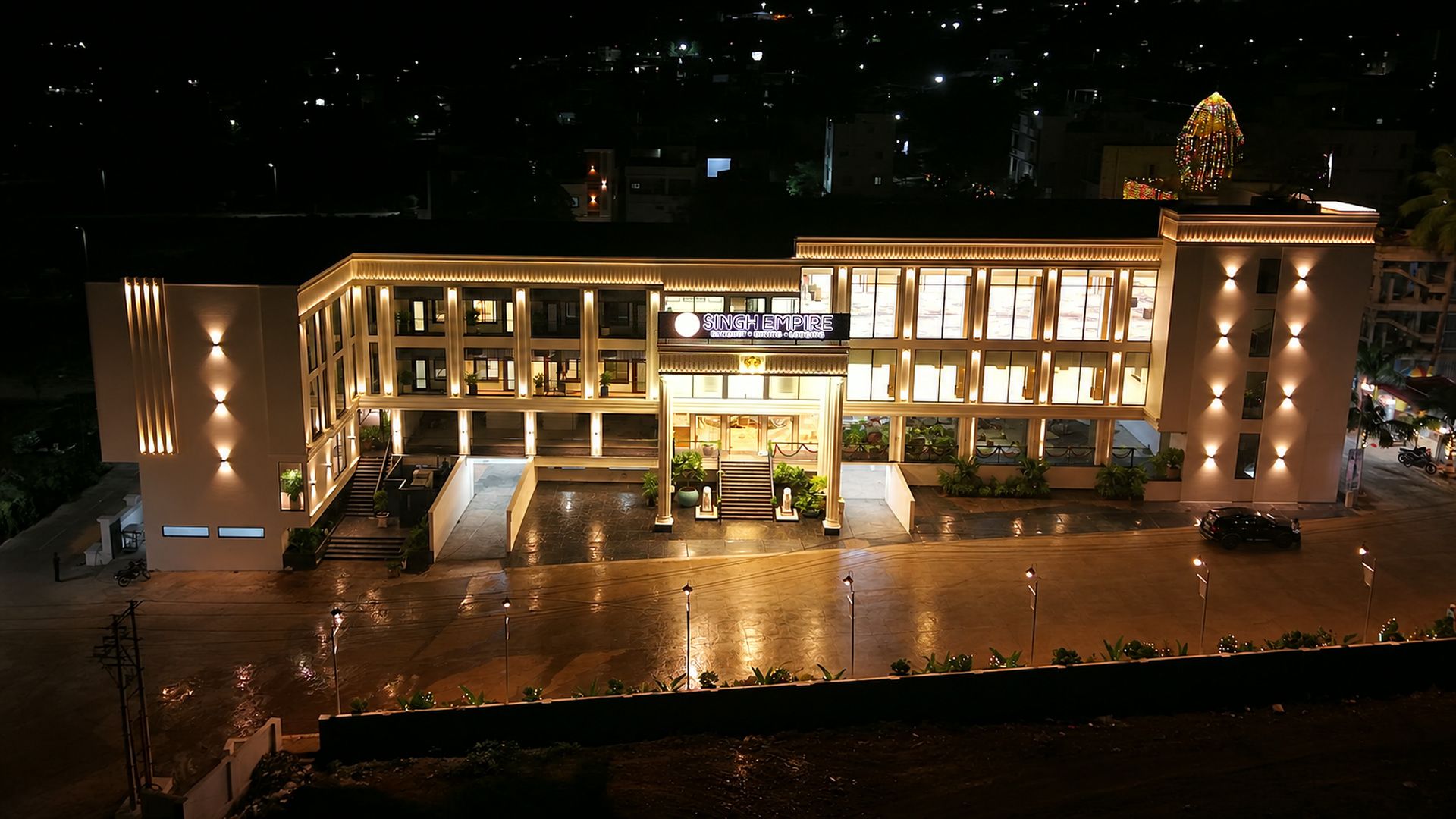 A multi-story hotel with a prominent entrance, a well-lit facade, and a parking area.