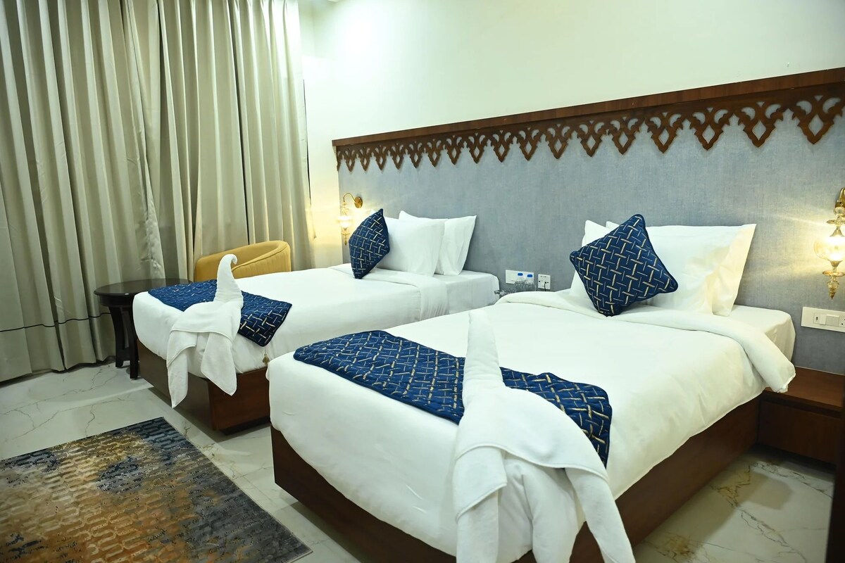 Ein Hotelzimmer mit zwei Betten, einem kleinen Tisch und einem Stuhl.
