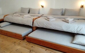 A room with two beds, each with a wooden frame and grey bedding. There are wall-mounted light fixtures on either side of the beds. - Holiday home near the beaches (Batz-sur-Mer)