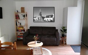 A living room with a dark sofa, a round coffee table, a bookshelf, and a framed picture on the wall. - Holiday home near the beaches (Batz-sur-Mer)