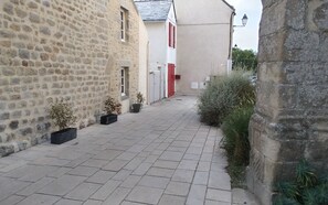 A narrow paved alleyway flanked by stone buildings with potted plants. - Holiday home near the beaches (Batz-sur-Mer)