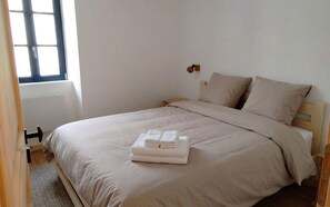 A bedroom with a bed, a window, and a wall-mounted light fixture. - Holiday home near the beaches (Batz-sur-Mer)