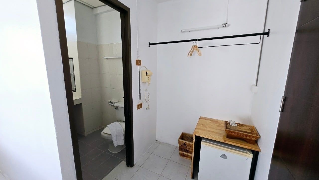 A bathroom with a toilet, a small wooden table, and a towel rack.