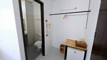 A bathroom with a toilet, a small wooden table, and a towel rack.