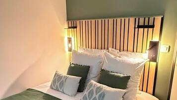A bed with a wooden headboard, multiple pillows, and bedside lamps.