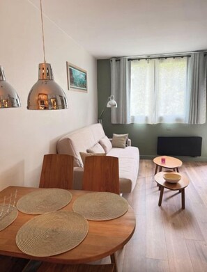 Una sala moderna con sofá, mesa de comedor y dos mesitas auxiliares.