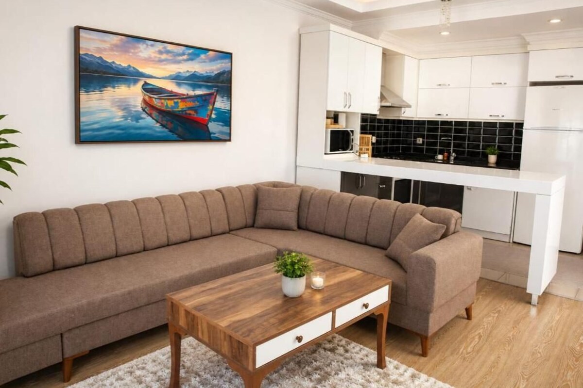 Una sala de estar moderna con un sofá seccional, una mesa de centro de madera y un cuadro de un barco en el agua.