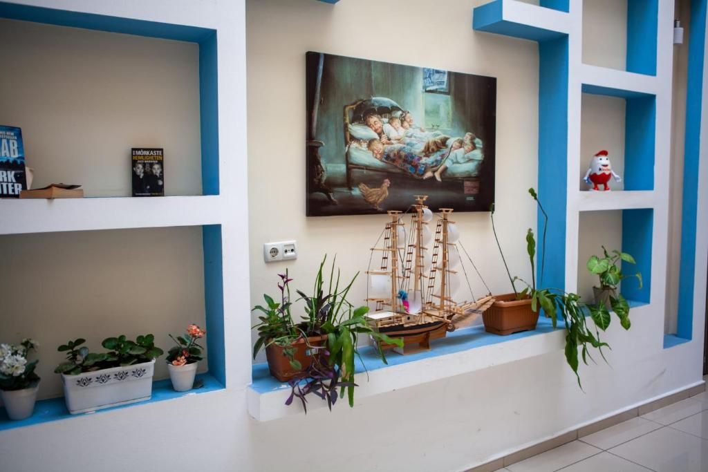 Una habitación con un cuadro, un modelo de barco y plantas en macetas.