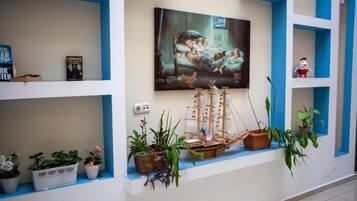 Una habitación con un cuadro, un modelo de barco y plantas en macetas.