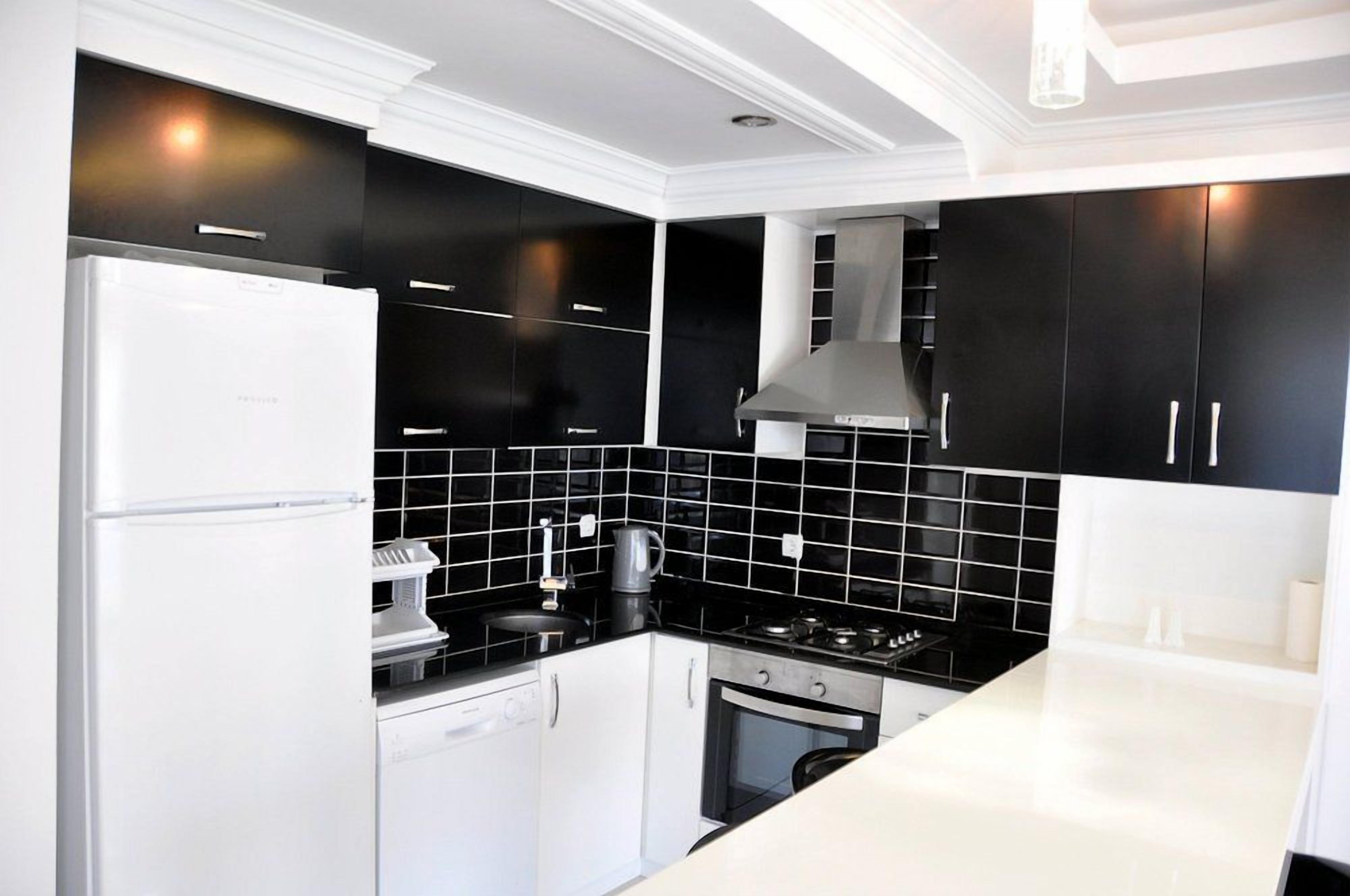 Una cocina moderna con armarios negros, un refrigerador blanco y una estufa.