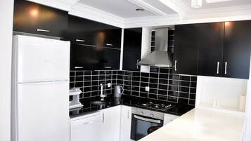 Una cocina moderna con armarios negros, un refrigerador blanco y una estufa.