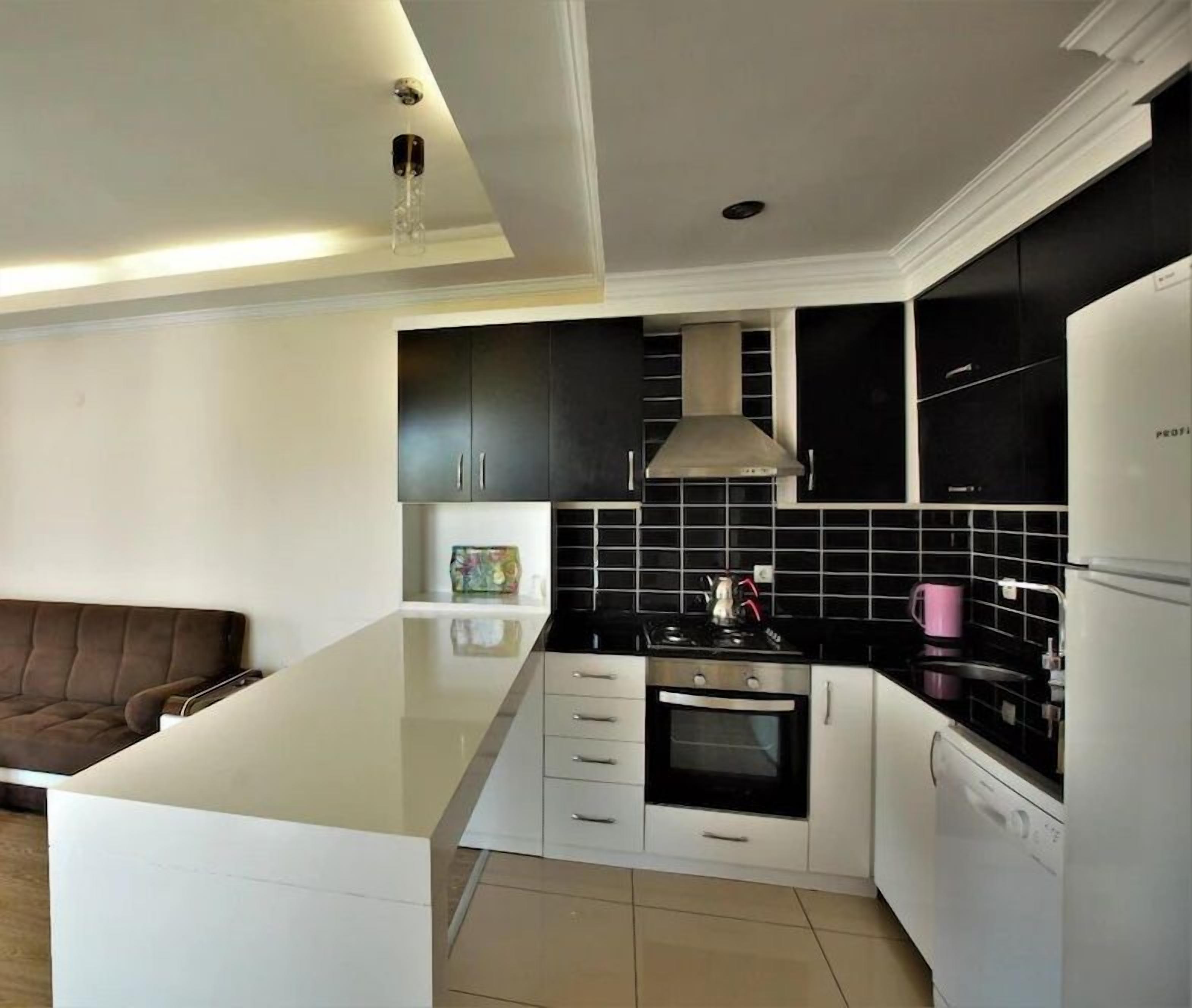 Una cocina moderna con una isla central, armarios negros y un refrigerador blanco.