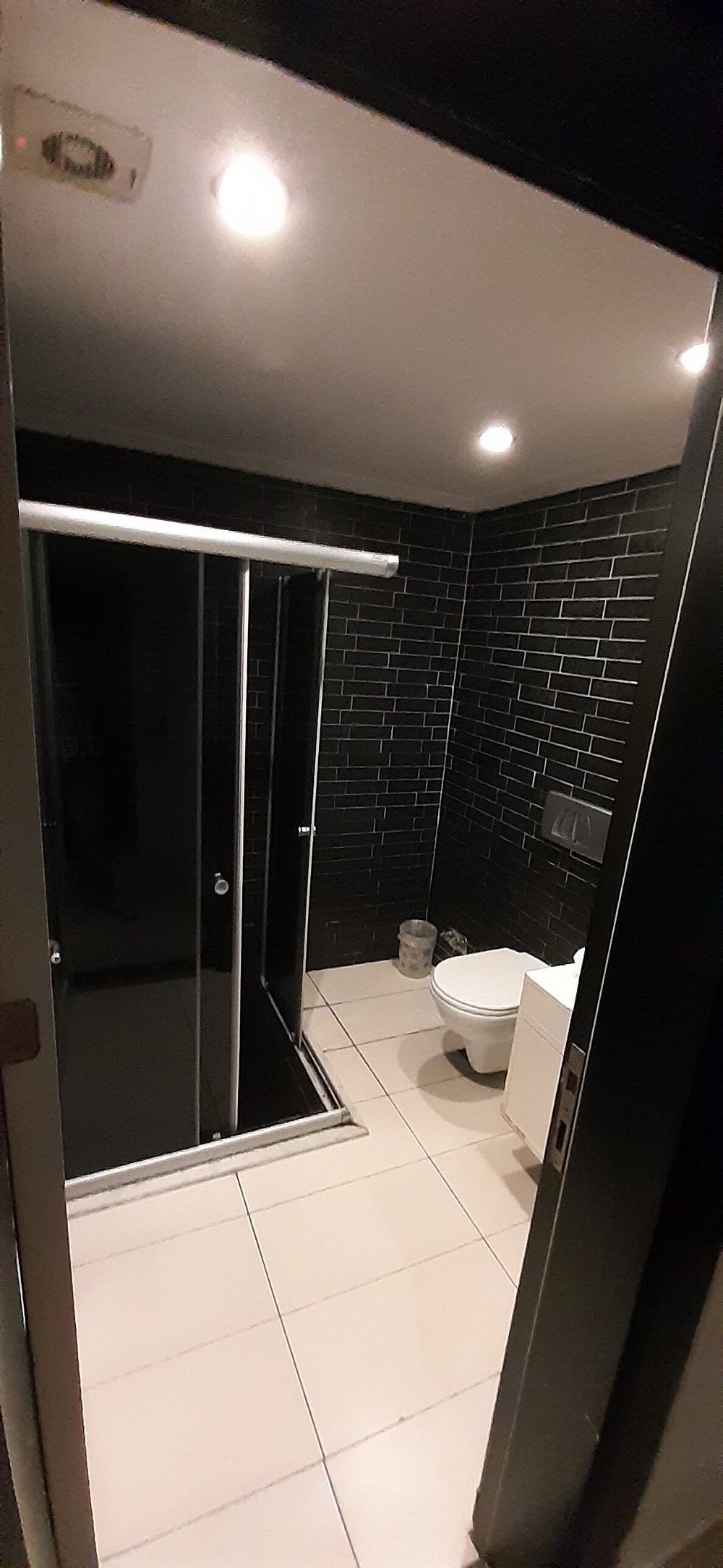 Un baño moderno con cabina de ducha de vidrio, inodoro y lavamanos.