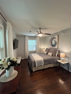 A bedroom with a bed, bedside lamp, artwork, and a ceiling fan. - 3 Bedroom, 2 Full Bath Luxurious Park Circle Retreat (North Charleston)