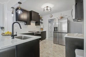 A modern kitchen with a central island, stainless steel appliances, and a marble countertop. - 3 Bedroom, 2 Full Bath Luxurious Park Circle Retreat (North Charleston)