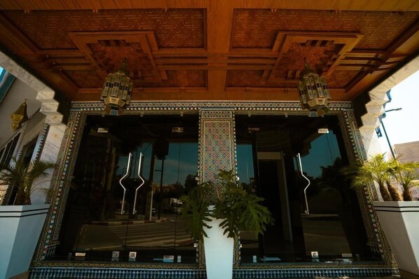 A building entrance with a wooden ceiling, decorative tiles, and two large lanterns.