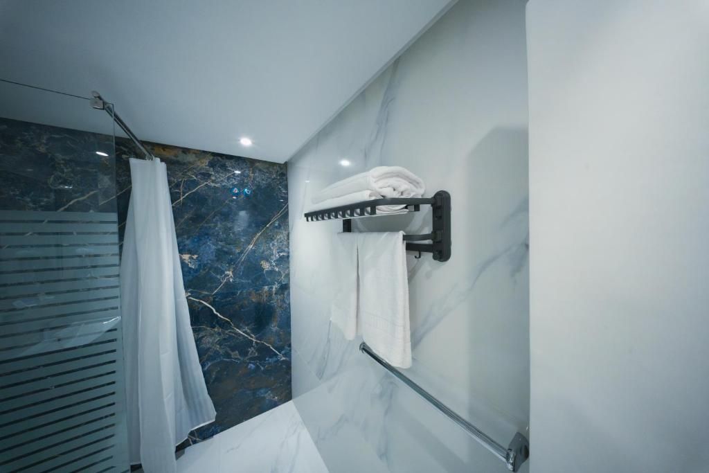 Un baño con pared de mármol, toallero y cortina de ducha.