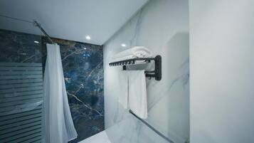 Un baño con pared de mármol, toallero y cortina de ducha.