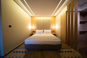 A hotel room with a bed, bedside tables, and a headboard.