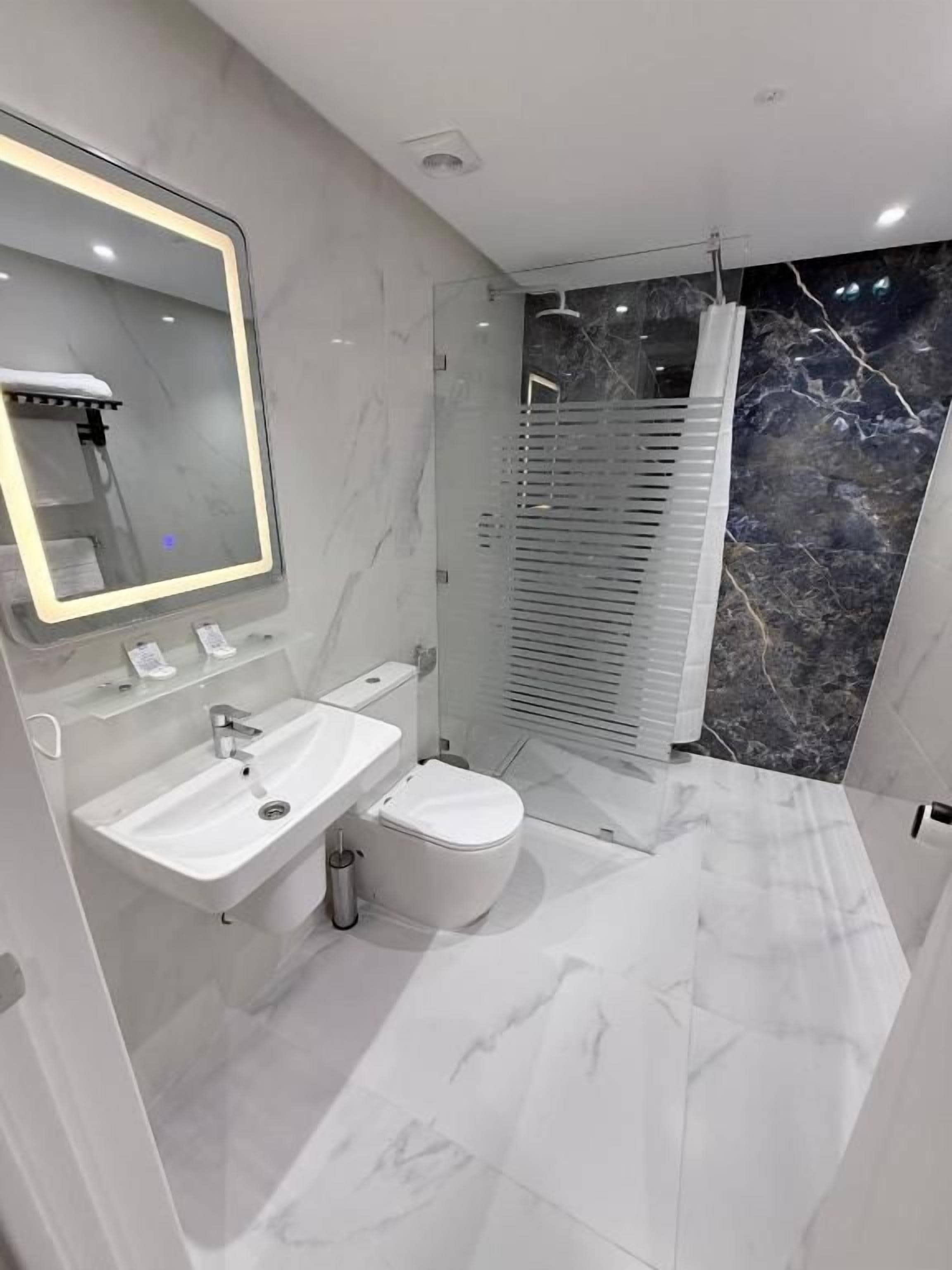 Un baño moderno con tocador, lavamanos, espejo y ducha.