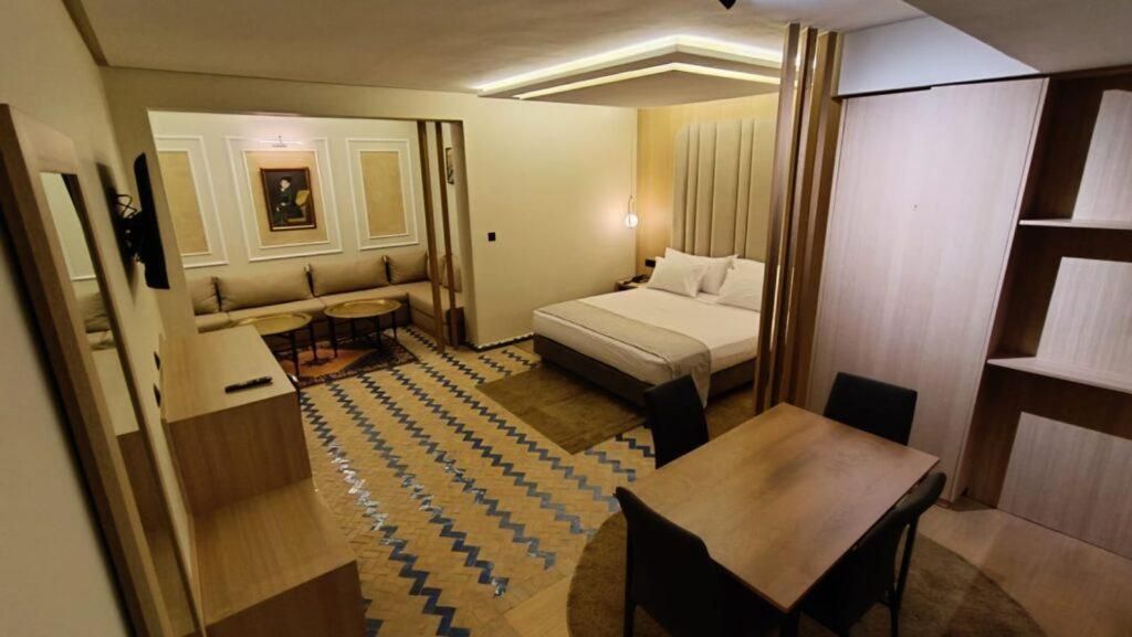 Ein kleines Hotelzimmer mit einem Bett, einem Schreibtisch, einem Stuhl und einem kleinen Tisch.