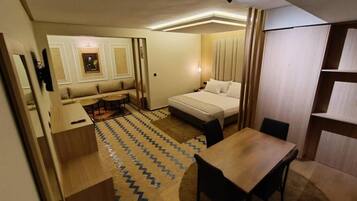 Ein kleines Hotelzimmer mit einem Bett, einem Schreibtisch, einem Stuhl und einem kleinen Tisch.