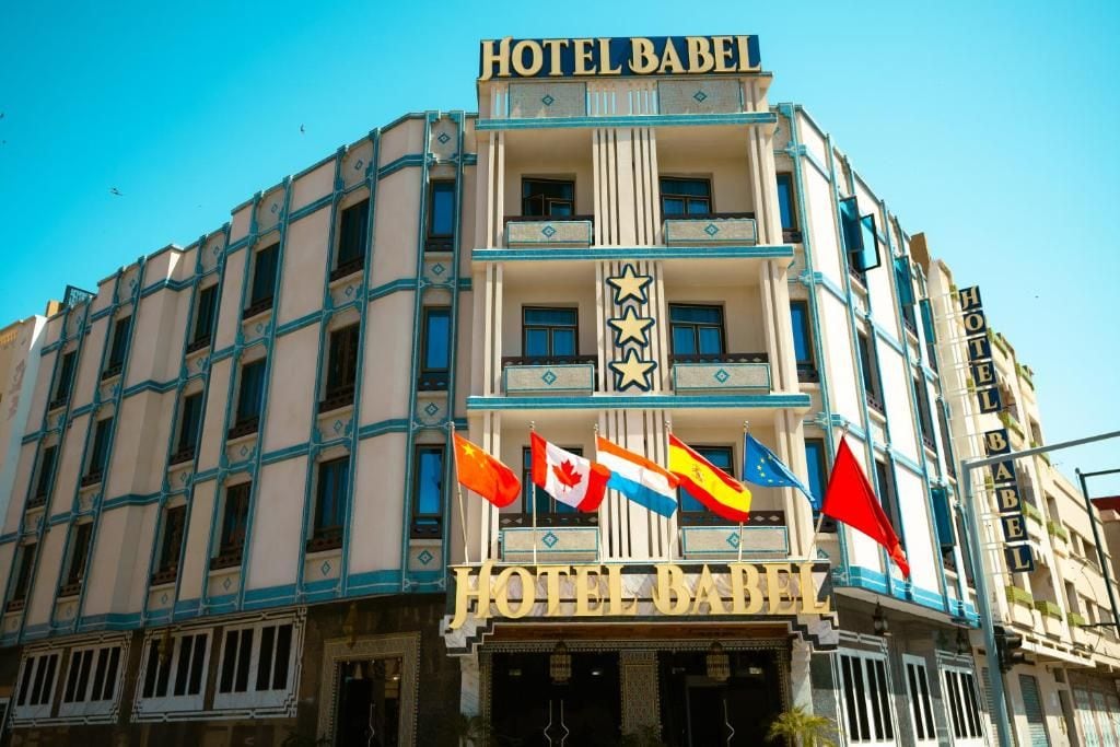 Un edificio con el letrero 'HOTEL BABEL' y varias banderas.