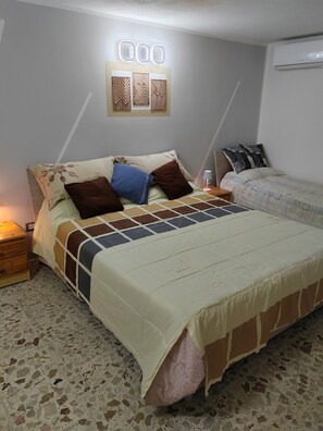 A bedroom with a bed, a nightstand, a wall-mounted light, and a ceiling fan. - Charming, cozy apartment on the mezzanine level, with a kitchen, bedroom, bathroom, and hallway (Alcamo)