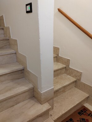 A staircase with beige steps and white walls, leading to a landing with a wooden handrail. - Charming, cozy apartment on the mezzanine level, with a kitchen, bedroom, bathroom, and hallway (Alcamo)
