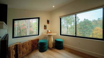 Une pièce dotée de grandes fenêtres, d’une table ronde en bois et d’un banc rembourré.