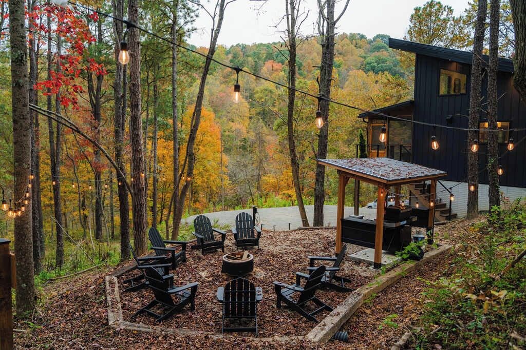 Een terras met Adirondack-stoelen, een vuurkorf en lichtslingers.
